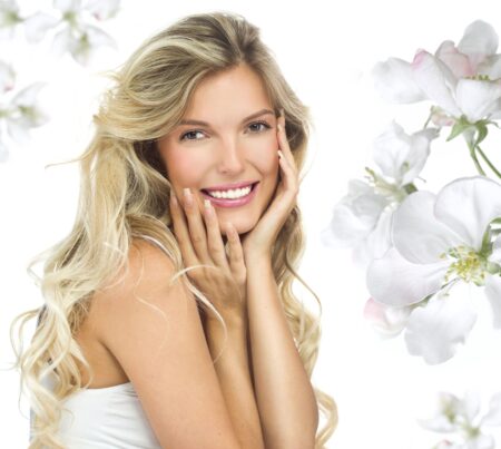 A smiling blonde woman whose teeth are perfectly white, such as might be achieved by internal bleaching.